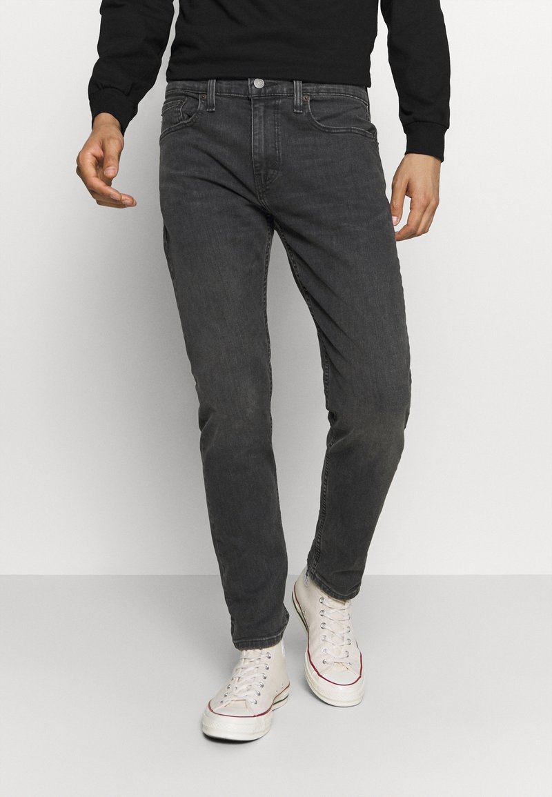 Šedé džíny se slim fit, se pěti kapsami, zapínáním na knoflík a jemným vyblednutím. K tomu bílé tenisky s vysokou špičkou.