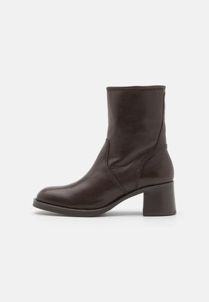 Dark brown leather ankle boot with block heel, round toe, and stitched detailing, shown in side profile on light background.