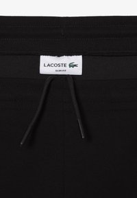 Zwarte slim-fit broek met een trekkoord in de taille. Voorzien van een Lacoste label met een krokodillenlogo, een zachte stof en subtiele stikseldetails.