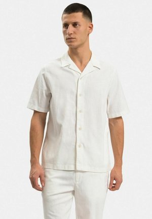 Kortsleeve, vit skjorta med knappar i lätt material; har en klassisk krage och en avslappnad passform, med en subtil textur.