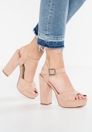 Escarpins en daim rose poudré avec plateforme et talon épais, dotés d'une bride à la cheville avec boucle métallique et d'un design à bout ouvert.