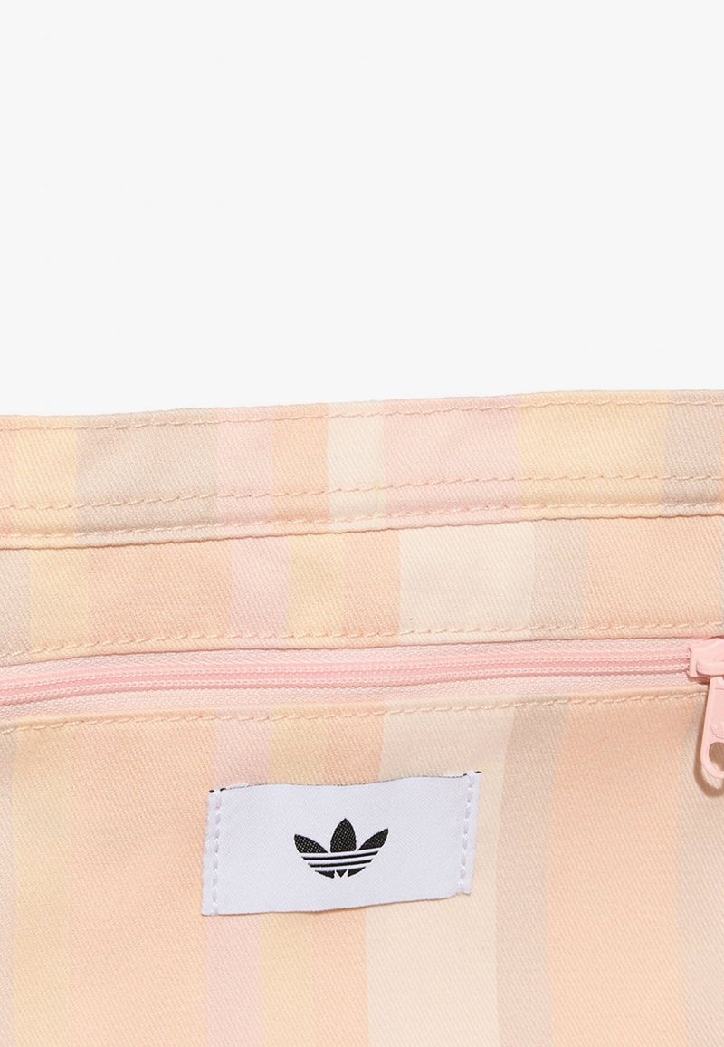 Nahaufnahme eines pastellgestreiften Stoffetuis mit einem pinkfarbenen Reißverschluss und einem weißen Etikett mit einem schwarzen dreiblättrigen Logo.
