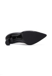 Chaussure à talons hauts noire avec un bout pointu et une surface en cuir verni lisse. Présente un talon mince et un accent rond et circulaire à l'arrière.