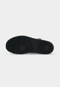 Μαύρη σόλα αθλητικού παπουτσιού Nike με κυκλικά σχέδια πέλματος και ορατό λογότυπο σε λευκό φόντο.