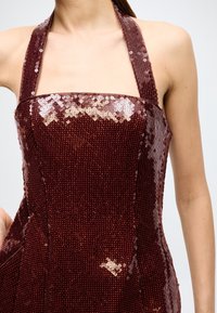 Burgundy sequined halter dress with a fitted bodice. Smooth texture with shiny sequins, square neckline, and thick straps.