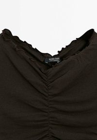 Brown top with a V-neckline and gathered texture, featuring a wavy edge finish. Label reads "Massimo Dutti," indicating brand origin from Morocco.