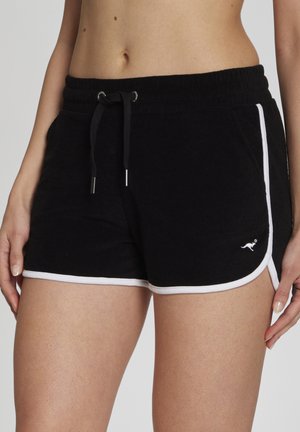 Schwarze Frottee-Shorts mit weißem Saum, getragen von einer Person, mit elastischem Bund mit Kordelzug und kleinem Känguru-Logo auf der linken Seite.
