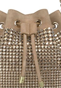 Bolso de cubo de ante beige con cierre de cuerda, adornado con cristales reflectantes y detalles de herrajes en tono dorado.