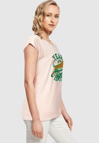 Lichtroze katoenen T-shirt met een V-hals en opgerolde korte mouwen. Heeft een afbeelding van een tijger en de tekst "Jaar van de Tijger" in het groen.