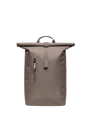 Plecak w kolorze taupe z klapką rolką, z pionową kieszenią na suwak z przodu i uchwytem u góry, wyposażony w pasek z klamrą i logo "GOT BAG" blisko dołu.