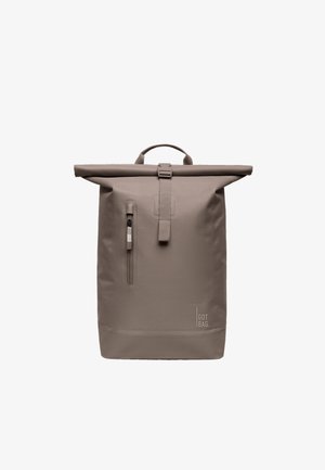 Plecak w kolorze taupe z klapką rolką, z pionową kieszenią na suwak z przodu i uchwytem u góry, wyposażony w pasek z klamrą i logo "GOT BAG" blisko dołu.