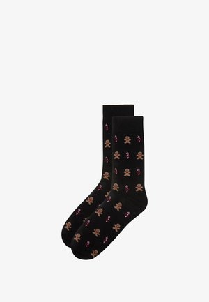 Black socks with gingerbread man and candy cane pattern. Made from a soft fabric, featuring a ribbed top and smooth texture.