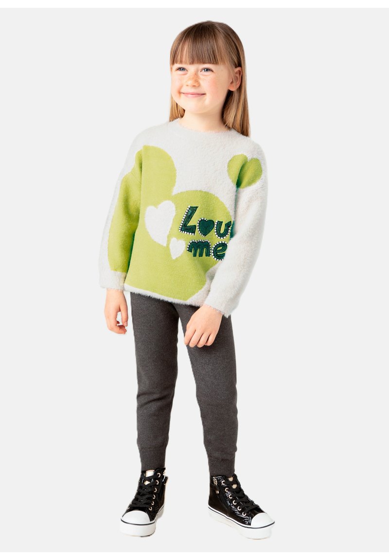 Maglione bianco morbido con cuori verdi e il testo "Love me", abbinato a leggings grigi e scarpe da ginnastica alte nere con suola bianca.