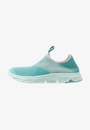 Zapatilla deportiva azul claro sin cordones con parte superior de malla transpirable, lengüeta en la parte superior y suela ligera y texturizada diseñada para comodidad y uso casual.