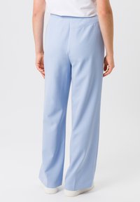 Lichtblauwe, wijde broek gemaakt van gladde stof. Heeft een hoge taille en subtiele plooien, met een schoon, eenvoudig ontwerp.