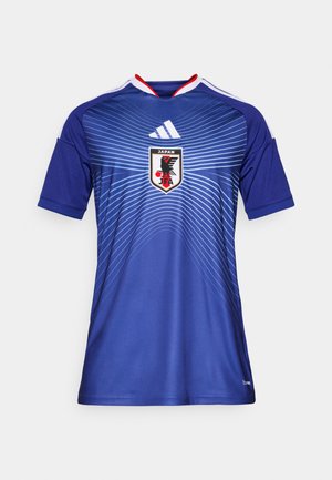 Μπλε αθλητική φόρμα με γεωμετρικό σχέδιο κυμάτων, κόκκινες και λευκές λεπτομέρειες στον γιακά και το λογότυπο της Ποδοσφαιρικής Ομοσπονδίας της Ιαπωνίας στη μέση.