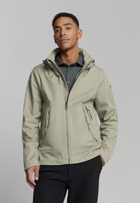 Licht khaki waterdichte jas met een ritssluiting aan de voorkant, verstelbare capuchon en zijzakken, gemaakt van soepele, duurzame stof.