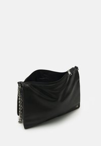 Borsa a mano in pelle nera con una texture liscia, chiusura con zip, tracolla in catena argentata e un sottile dettaglio del logo sul lato. L'interno è semplice.