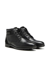 Botas de tobillo de cuero negro con un acabado suave, punta redonda, cordones en la parte delantera y un panel texturizado en los costados. Suela de goma para proporcionar agarre.