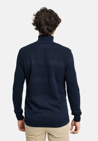 Marineblauer Pullover mit hohem Kragen und strukturiertem Muster sowie glatten Abschnitten. Strickstoff, lange Ärmel und gerippte Bündchen. Einfaches Design, ohne Verzierungen.