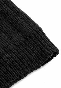 Czarna, prążkowana dzianina z zagiętym brzegiem, ukazująca ciasno tkany teksturowany wzór na białym tle.