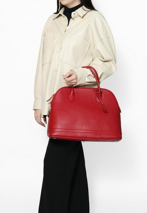 Rode leren handtas met een gestructureerde vorm, twee bovenhandvatten en een ritssluiting. Het oppervlak is getextureerd en heeft subtiele stikdetails.