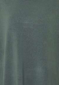 Pull tricoté vert foncé, présentant une texture lisse et un col rond. Le tissu affiche une légère brillance et un tissage régulier.