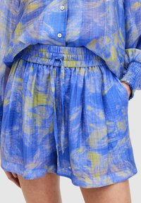 Šorts u plavoj i žutoj uzorak s elastičnim pojasom, bočnim džepovima i opuštenim krojem. Napravljen od lagane, teksturirane tkanine.
