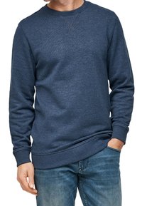 Sudadera azul marino hecha de tejido suave, con cuello redondo, mangas largas y puños y dobladillo acanalados. Ajuste casual sobre unos vaqueros.