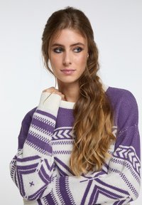 Pullover lavorato a maglia viola e bianco con motivi geometrici, maniche lunghe e scollo a giro. La texture appare morbida e spessa.