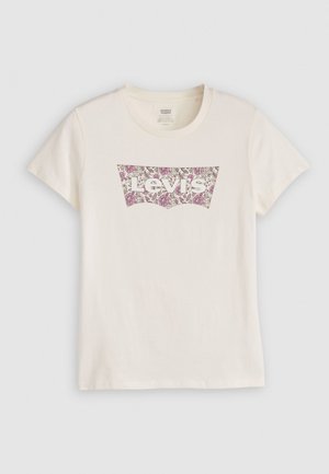 Valkoinen puuvillapaita, jossa on vaaleanpunaisista ja maroonin värisistä kukkakuviosta tehty Levi's-logo perinteisessä logo-tyylissä. Lyhythihaisena.