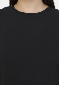 Sort kortærmet top med rund halsudskæring, der har en glat, blød tekstur og et simpelt, minimalistisk design.