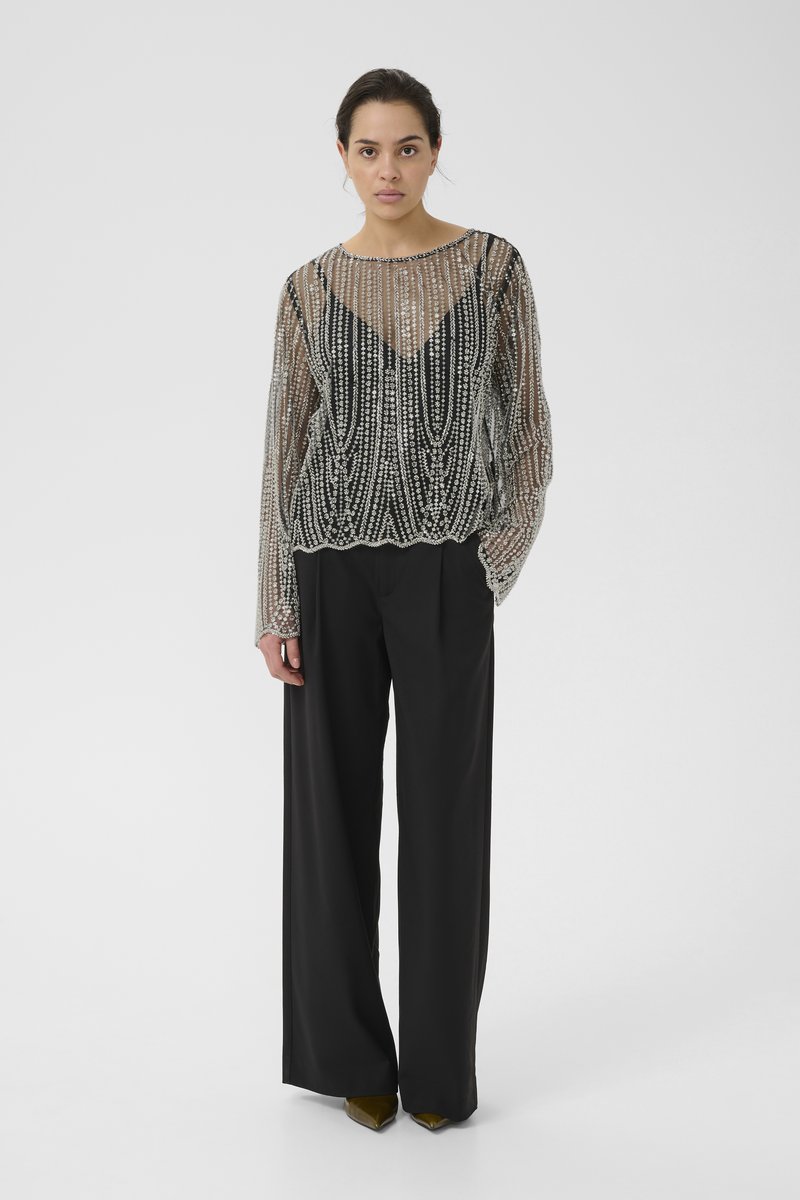 Black wide-leg pants paired with a sheer, intricately beaded long-sleeve top. The top features a V-neck and scalloped hem.