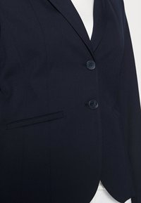 Blazer blu navy realizzato in tessuto testurizzato con una vestibilità su misura, dotato di chiusura a due bottoni e una tasca laterale.