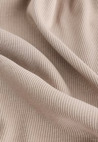 Tissu beige clair côtelé, présentant de fines rayures verticales, texture lisse et tombé souple, idéal pour les vêtements ou la tapisserie.