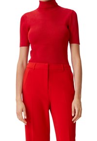 Camiseta de cuello alto de manga corta en rojo, confeccionada en tejido acanalado, con un diseño ajustado. Combinada con pantalones de talle alto a juego en rojo, que destacan una silueta elegante.