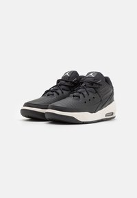 Czarne syntetyczne sneakersy z perforowaną teksturą, białymi akcentami i widoczną jednostką powietrzną. Posiadają sznurówki i wyściełany kołnierz dla wsparcia.