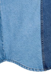 Panneaux de tissu en denim bleu bicolore cousus ensemble avec des coutures marron visibles et un ourlet courbé sur le bord inférieur.