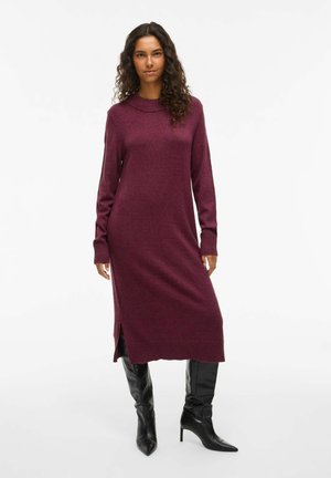 Abito lavorato a maglia bordeaux con maniche lunghe, scollatura a costine, spacchi laterali e vestibilità slim, abbinato a stivali neri al ginocchio con punta.