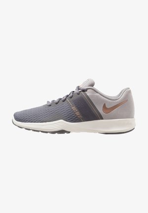 Chaussure de course Nike grise et noire avec semelle blanche, logo Swoosh bronze, lacets et bande de texte "Just Do It" sur le côté.