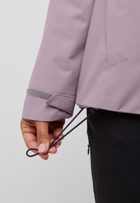 Manica di giacca viola con strap in Velcro, dotata di un regolatore con cordoncino all'orlo. Tessuto morbido, materiale leggero, senza motivi visibili.