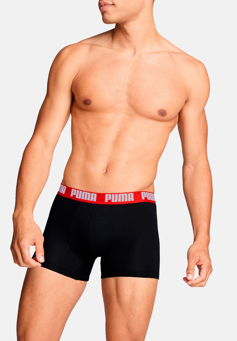 Schwarze Boxershorts mit einem roten Puma-Logo am Bund. Der Stoff wirkt glatt und dehnbar, passt sich der Körperform an.