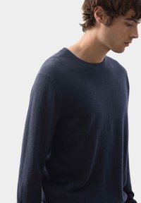Maglione blu navy in tessuto morbido, con scollo a girocollo e maniche lunghe, dal taglio rilassato e design minimalista.