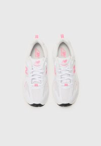 Baskets de course blanches avec des accents roses, dotées d'une tige en filet, d'une semelle rembourrée et d'un logo distinct sur le côté et sur la languette.