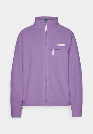 Fioletowa kurtka z polaru z wysokim kołnierzem, pełnym zapięciem na zamek z przodu oraz kieszenią na piersi z małym zamkiem. Miękka w dotyku i z minimalistycznym wzornictwem.