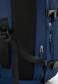 Námořnický modrý batoh s texturovanou černou síťovinou, zipy a nastavitelními popruhy. Vyznačuje se elegantním designem a pevnými materiály.