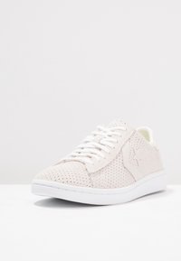 Vita perforerade syntetiska sneakers med en slät vit sula och vita snören. Har en subtil logotyp på sidan och ett vadderat inre.