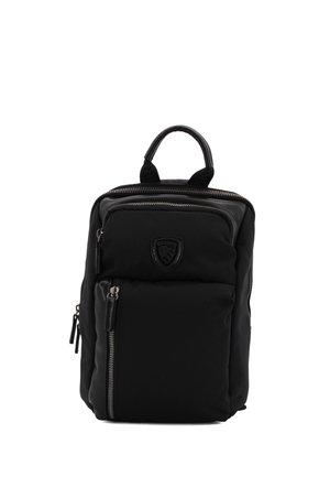 Zaino in nylon nero con manico superiore, tasche anteriori con zip, logo in rilievo e accessori in argento. Superficie texture con sezioni imbottite.