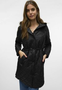 Zwarte gewatteerde jas met een cinched taille, trekkoordcapuchon en twee zijzakken; heeft een gladde, glanzende textuur.