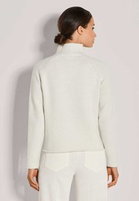 Weißer, gerippter Rollkragenpulli mit langen Ärmeln und geradem Schnitt. Hat einen leicht asymmetrischen Saum und Raglanärmel.